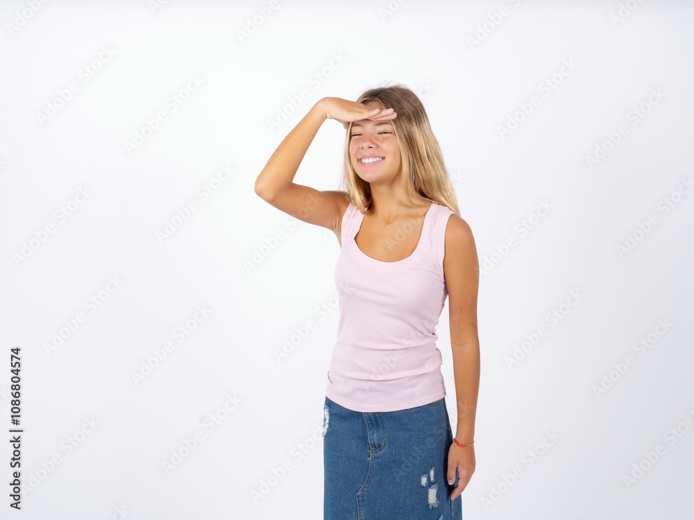 Beautiful teen girl wearing sleeveless t-shirt very happy and smiling looking far away with hand over head. Searching concept. Beautiful teen girl wearing sleeveless t-shirt very happy and smiling looking far away with hand over head. Searching concept.