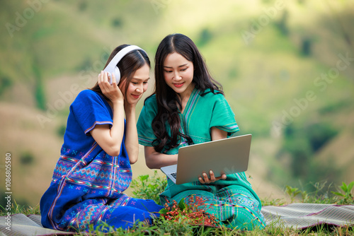 Woman sitting on a meadow using laptop online shopping happily