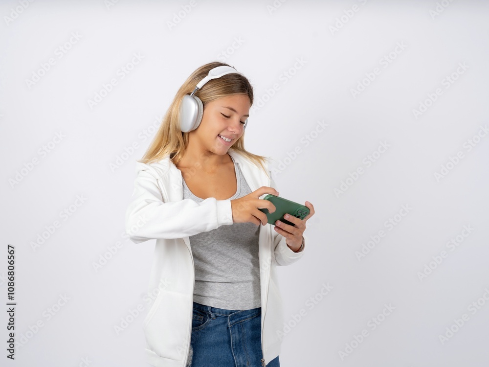 Beautiful teen girl wearing white jacket holding in hands cell playing video games or chatting