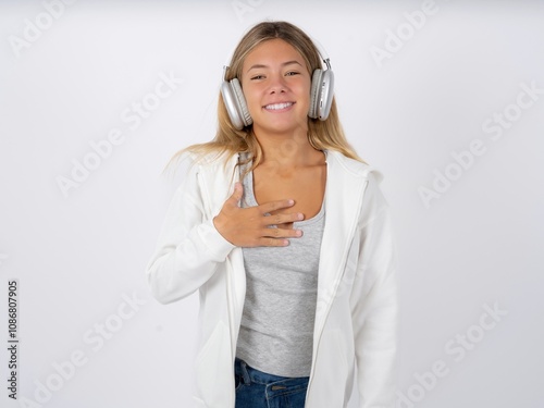 Beautiful teen girl wearing white jacket smiles toothily cannot believe eyes expresses good emotions and surprisement photo