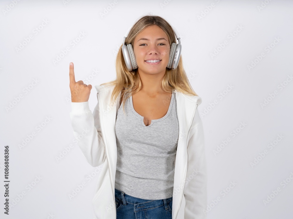 Beautiful teen girl wearing white jacket smiling and looking friendly, showing number one or first with hand forward, counting down Beautiful teen girl wearing white jacket smiling and looking friendly, showing number one or first with hand forward, counting down