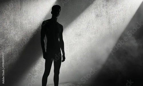 A silhouetted figure stands in a dimly lit space, evoking a sense of solitude and introspection.