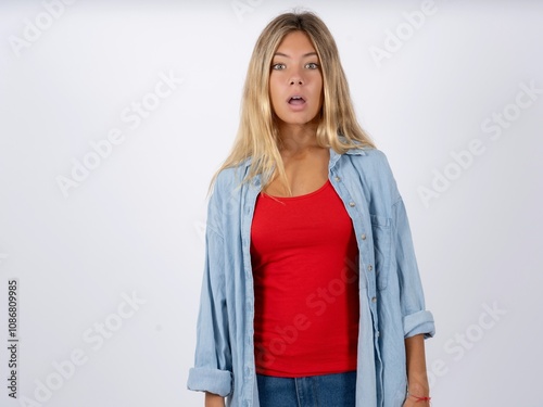 Shocked Beautiful teen girl wearing denim jacket stares bugged eyes keeps mouth opened has surprised expression. Omg concept photo