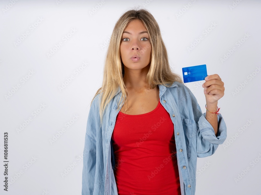 Photo of Beautiful teen girl wearing denim jacket amazed shocked hold credit card payment Photo of Beautiful teen girl wearing denim jacket amazed shocked hold credit card payment