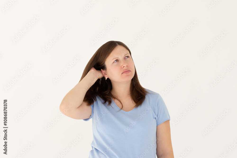 Young beautiful girl with long ginger hair wearing blue t-shirt. freelancer looking away with confused disappointed expression, scratching head. student not remembers information for exam Young beautiful girl with long ginger hair wearing blue t-shirt. freelancer looking away with confused disappointed expression, scratching head. student not remembers information for exam