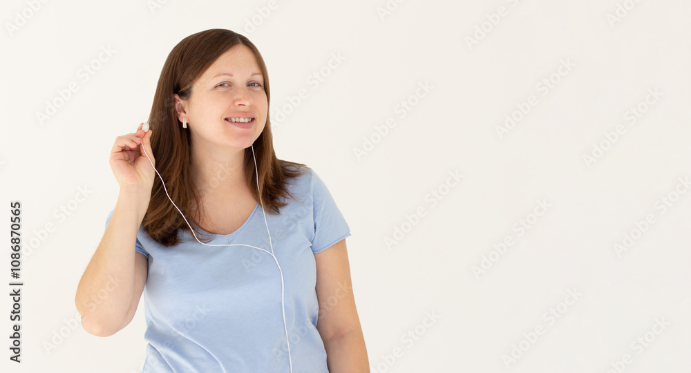 Image of a happy young beautiful woman posing isolated over white wall background listening music with earphones. Image of a happy young beautiful woman posing isolated over white wall background listening music with earphones.