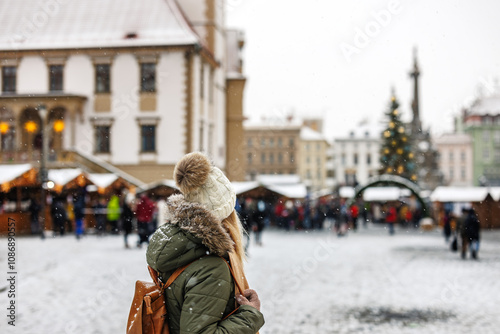 Woman tourist is going to Christmas market at town square during Advent holiday. Lifestyle in city at winter