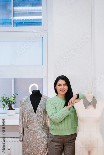 Smiling design professional standing amidst dummies in studio photo