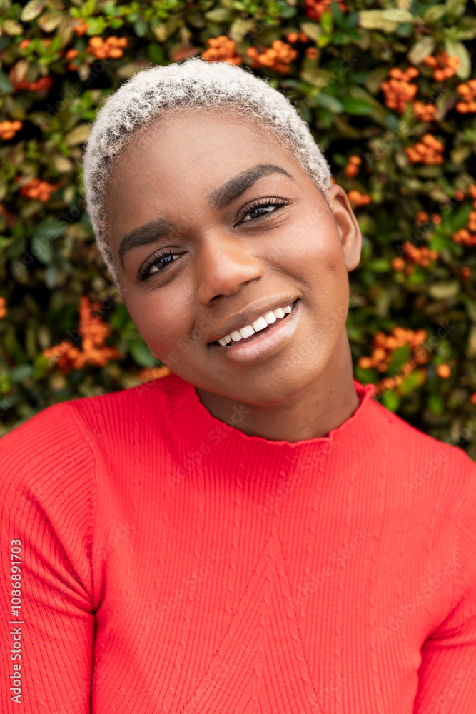 Smiling woman with short hair in front of flowering plant Smiling woman with short hair in front of flowering plant