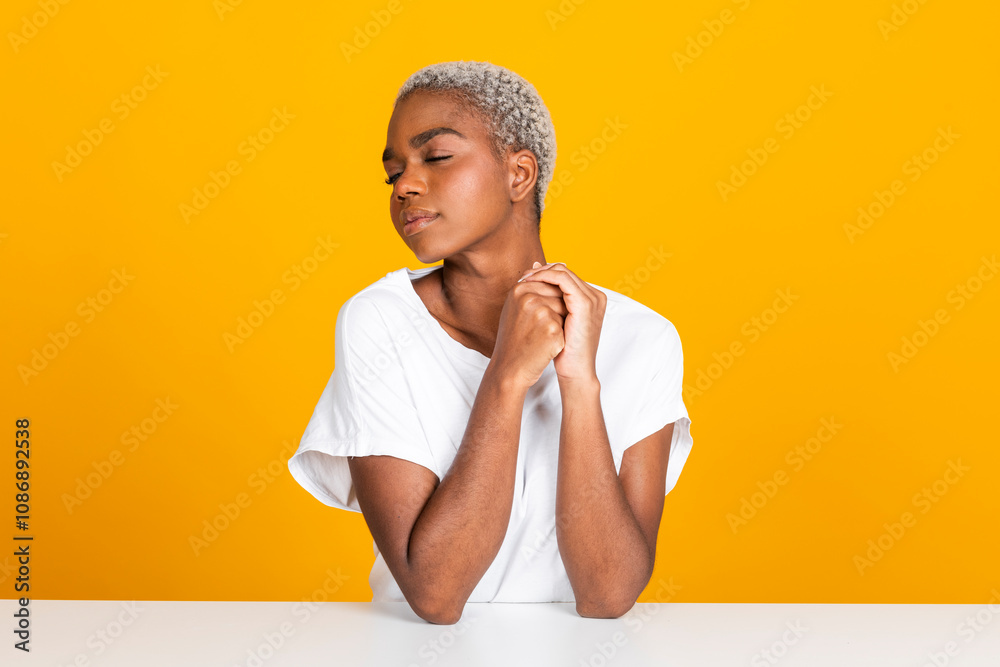 © Westend61 - Woman sitting with eyes closed at table against yellow background