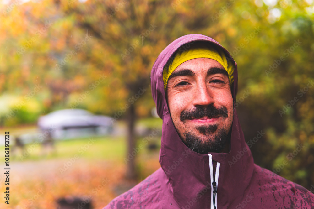 Smiling man wearing hooded jacket in park Smiling man wearing hooded jacket in park