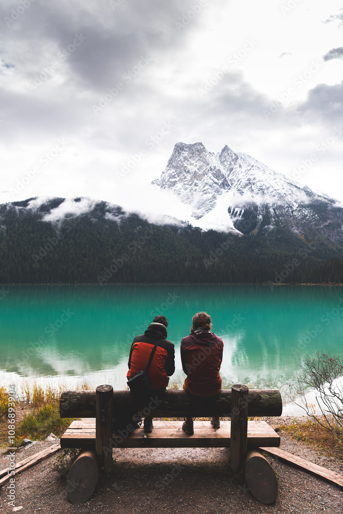 Friends sitting on bench near Emerald lake in Banff national park at Alberta, Canada Friends sitting on bench near Emerald lake in Banff national park at Alberta, Canada