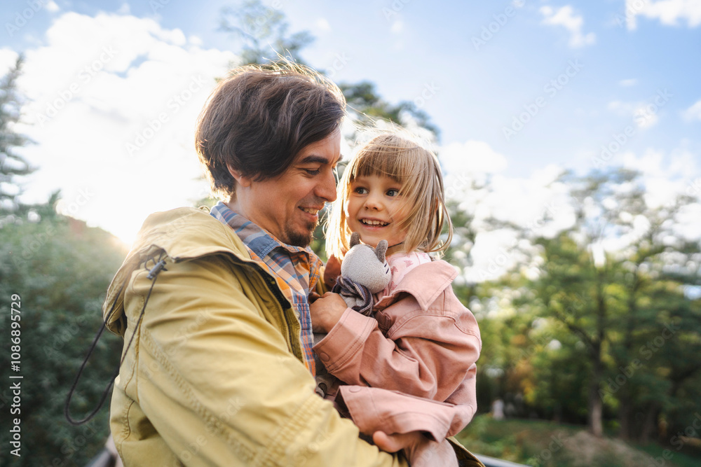 Smiling man carrying daughter with soft toy in park Smiling man carrying daughter with soft toy in park