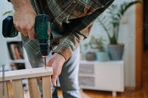 Man installing furniture with drill machine at home photo