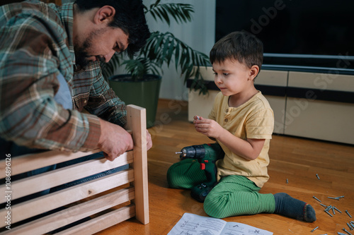 Father and son assembling furniture in living room at home photo