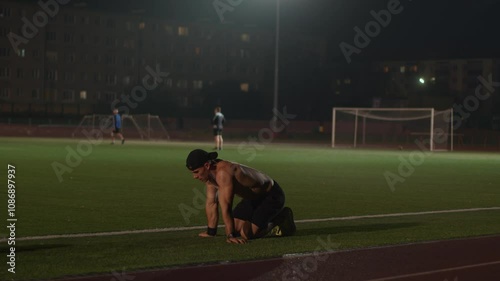 Young man in black shorts is training on edge of football field and resting while sitting on knees. Slow motion. Any bodyweight exercise is effective way to develop strength and muscle endurance