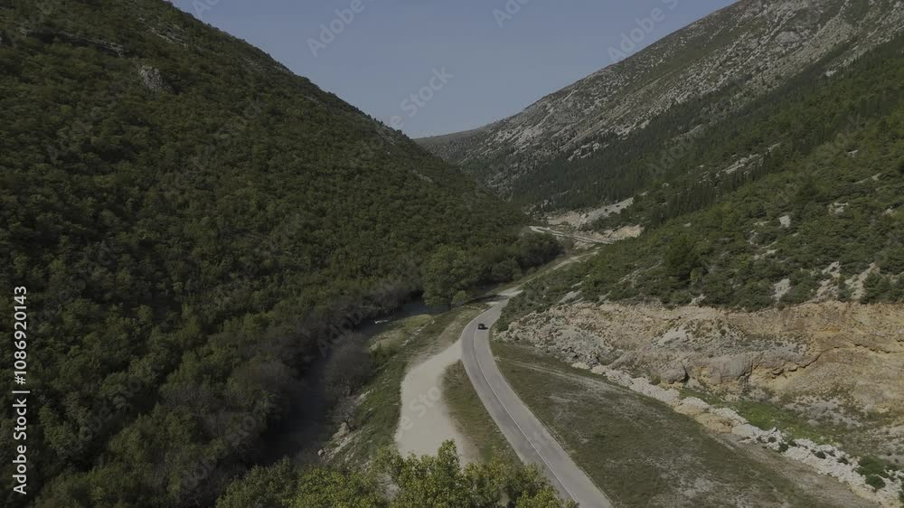 Drone video of a winding river surrounded by the mountains of Bosnia. The landscape is a unique combination of natural beauty and roads.
