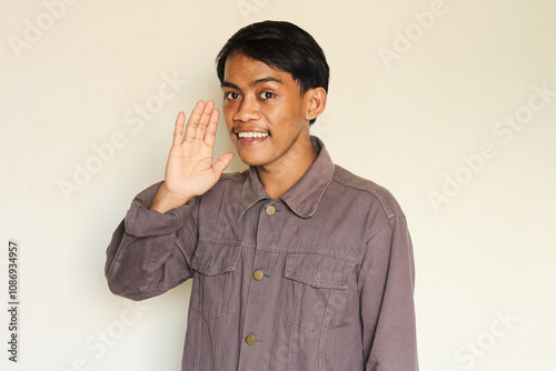 Young asian man who whispers while showing a cheerful face. isolated on a white background.