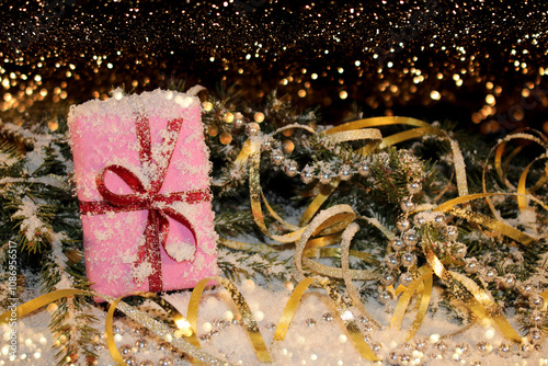 Christmas background with a pink gift on the background of a snow-covered green fir tree on a shiny background