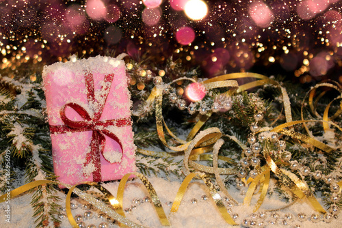 Christmas background with a pink gift on the background of a snow-covered green fir tree on a shiny background