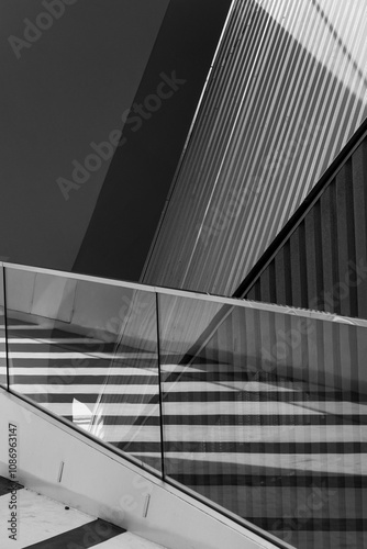 This image shows an abstract architectural scene characterized by sweeping diagonal lines, intersecting shadows, and sharp angles, creating a striking visual impression. photo