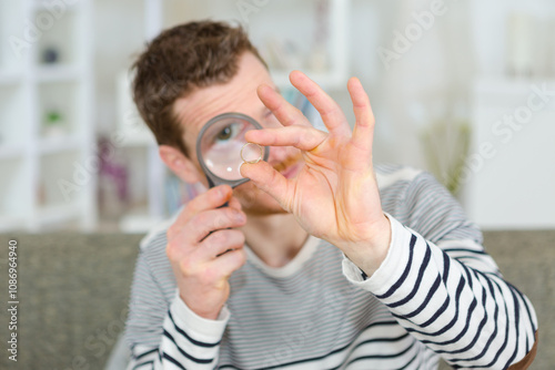 man looking though a magnifying glass at his coin collection photo