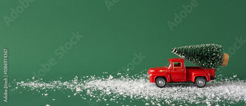 Tableau sur toile A charming vintage red toy truck carries a miniature Christmas tree across a snowy path