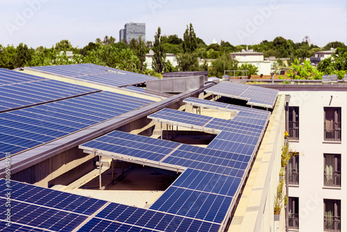 Solar panels on House Roof. Modern High-rise Residential Apartment Building with Solar Panel Station on Roof in Modern Green City.