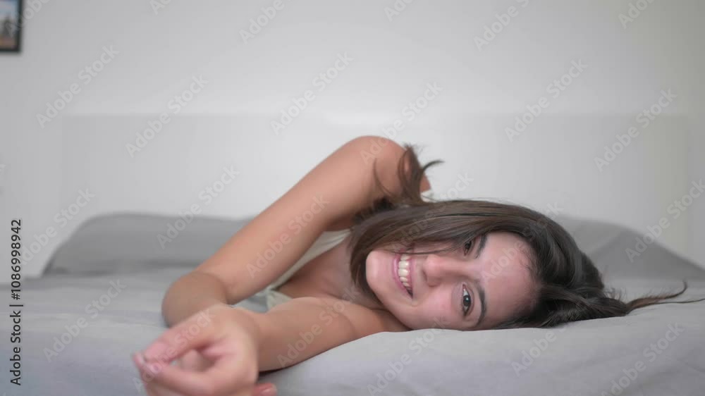 Girl happily rolling on bed, smiling at camera Girl happily rolling on bed, smiling at camera
