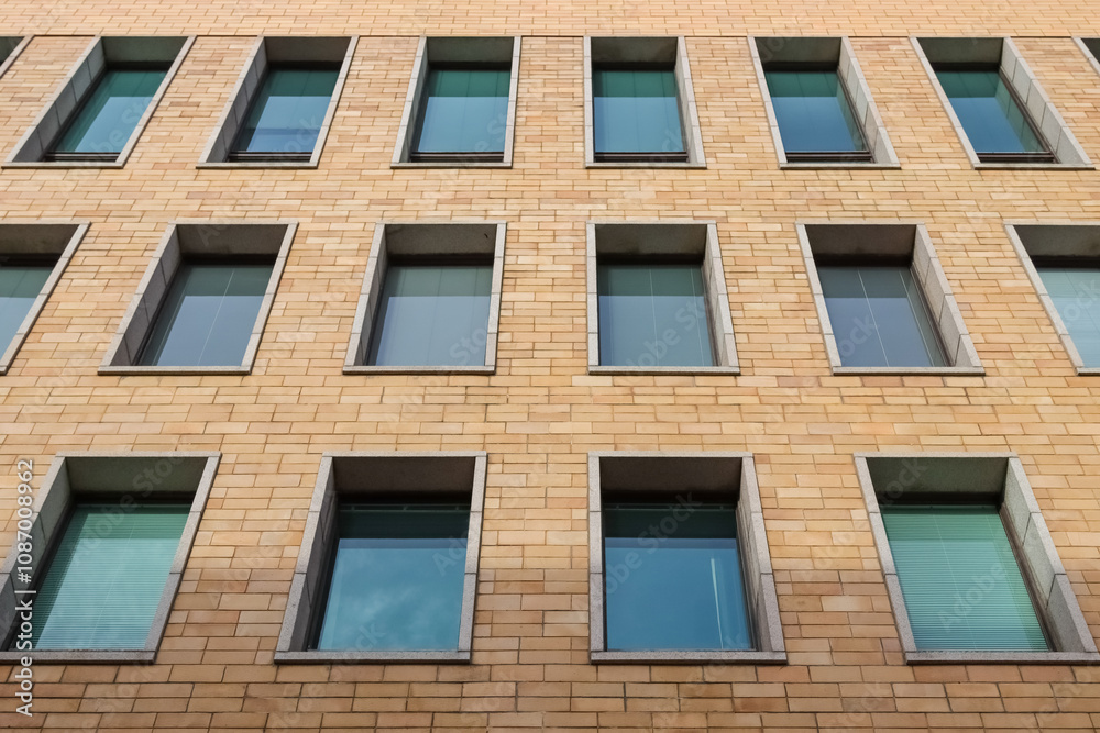 Building facade in Helsinki with symmetrical windows. Close-up view of a modern building facade with symmetrical brickwork and multiple windows, showcasing urban architecture and design. Building facade in Helsinki with symmetrical windows. Close-up view of a modern building facade with symmetrical brickwork and multiple windows, showcasing urban architecture and design.
