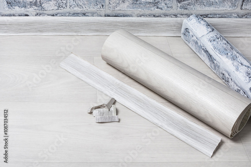 On the floor is a roll of linoleum, a baseboard and wallpaper. Construction materials for room renovation. Apartment or house renovation concept