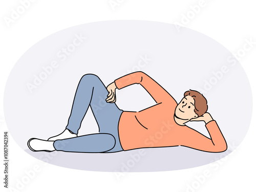 Man lies on floor with hand under head and with smile looks at screen, offering to relax and unwind. Happy guy lies on ground and smiles, feeling lazy orlacking initiative for personal growth.