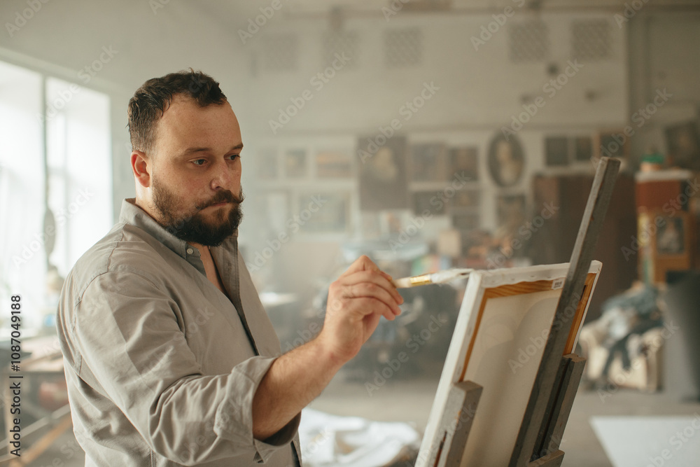 Fototapeta premium Male artist priming a canvas in his creative studio