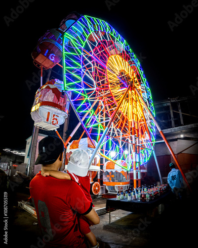 A father carries his toddler son at the night market