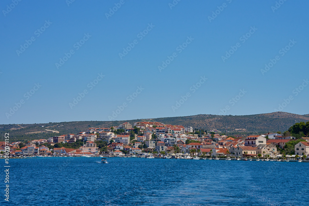 Seaside town with colorful coastal houses on hillside with boats docked along clear blue waters. Residential apartments for summer vacation on Adriatic Sea in Rogoznica, Croatia Seaside town with colorful coastal houses on hillside with boats docked along clear blue waters. Residential apartments for summer vacation on Adriatic Sea in Rogoznica, Croatia