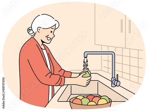 Elderly woman washes fruits in sink, standing in kitchen and observing rules of hygiene to avoid infection. Grandmother washes vegetables before preparing dinner, following recommendations of doctors