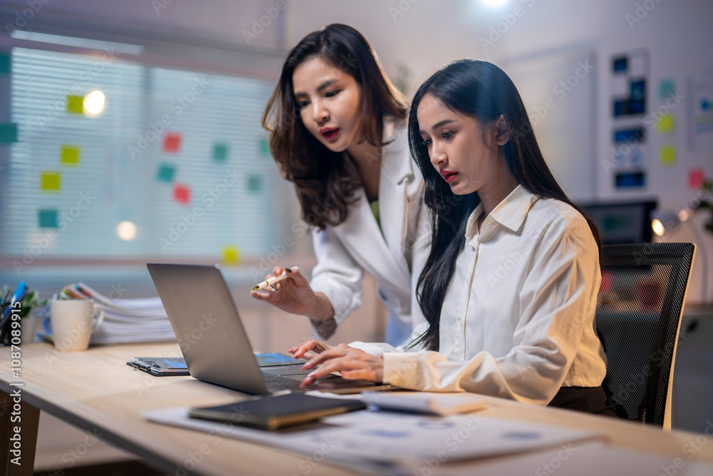 Two women are working on a laptop together Two women are working on a laptop together
