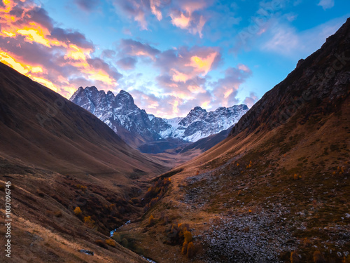 Fototapeta Naklejka Na Ścianę i Meble -  Autumn golden complex hills with amazing Caucasus mountains background, walking view at Juta, Georgia country. Brown and yellow colors mountain with stream, beauty sunrise landscape in the morning.