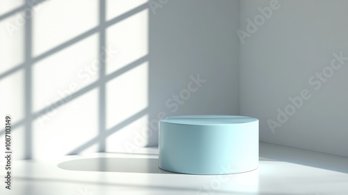 Pastel blue cylindrical podium on a white table, featuring soft shadows cast by natural light from a bright window against a minimalistic backdrop.