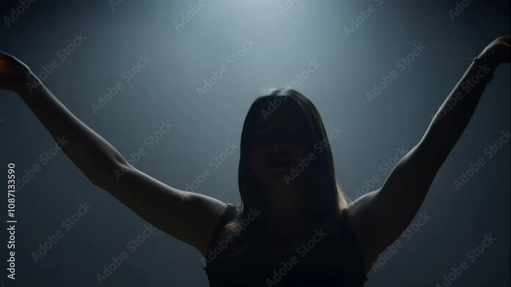 A silhouette of a woman singing passionately under a spotlight.