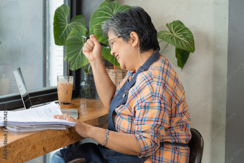 Senior barista female or employee concentrate on stacks of tax declaration bills, restaurant owner using laptop for bookkeeping control payment, multitask small business lifestyle financial budget