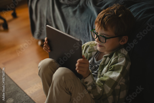 Boy using digital tablet while lying on bed at home photo