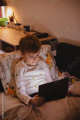 Boy using digital tablet on bed at home photo