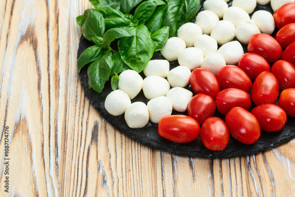 Basil leaves , cherry tomatoes and mozzarella cheese . In form italian flag food photography