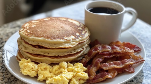 A hearty breakfast plate featuring a stack of fluffy golden pancakes, crispy bacon strips, scrambled eggs, and golden hash browns, served with a side of coffee and syrup for a classic morning meal.