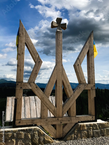 Wooden symbol with cross under dramatic sky and mountains. Coat of arms of Ukraine. photo