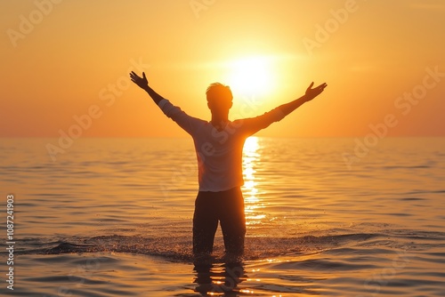 A silhouetted man raises arms in the ocean against sunset glow, evoking freedom and connection to nature's grandeur.