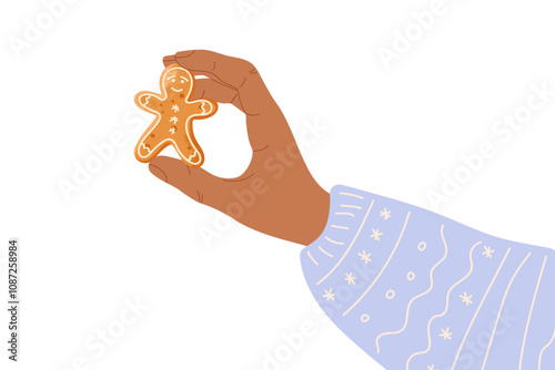 Human hand holding Gingerbread Man Cookie. Person wearing winter sweater. Homemade ginger pastries. Traditional Christmas baking. Merry Christmas and Happy New Year. Tasty homemade cookie