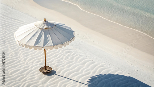 white beach umbrella casts shadow on soft, sandy shore, creating serene and inviting atmosphere. gentle waves and clear water enhance tranquil beach scene