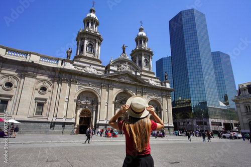 Tourism in Santiago de Chile. Rear view of traveler girl visiting Plaza de Armas square with the Metropolitan Cathedral of Santiago, Chile, South America.